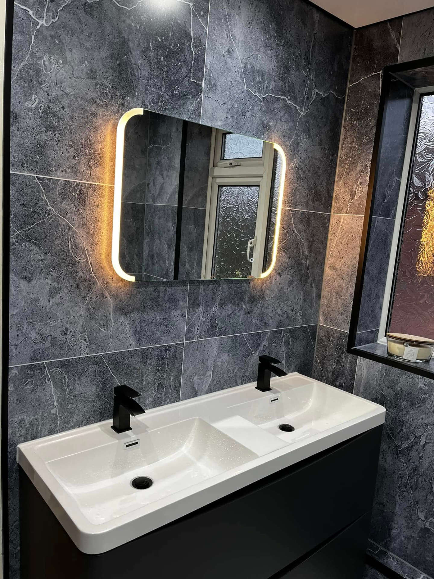 Finished bathroom with marble-effect tiling and illuminated mirror